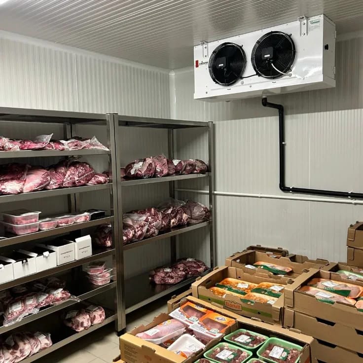 Walk-in cold room interior with evaporator fans and stocked shelving